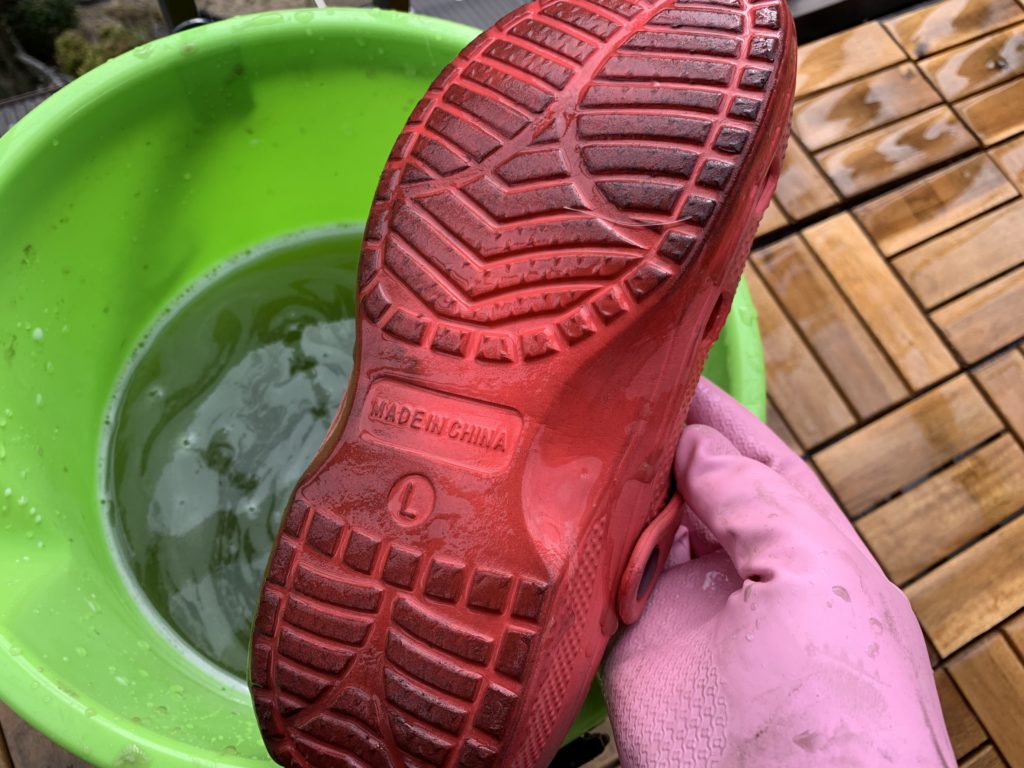 ベランダで使っている靴の裏側を洗う様子