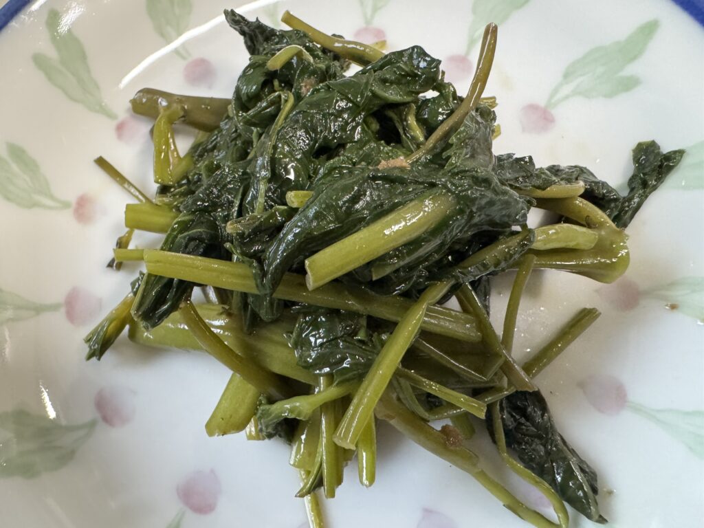 にんにくと炒めた空心菜(くうしんさい)をお皿に盛りつけた様子